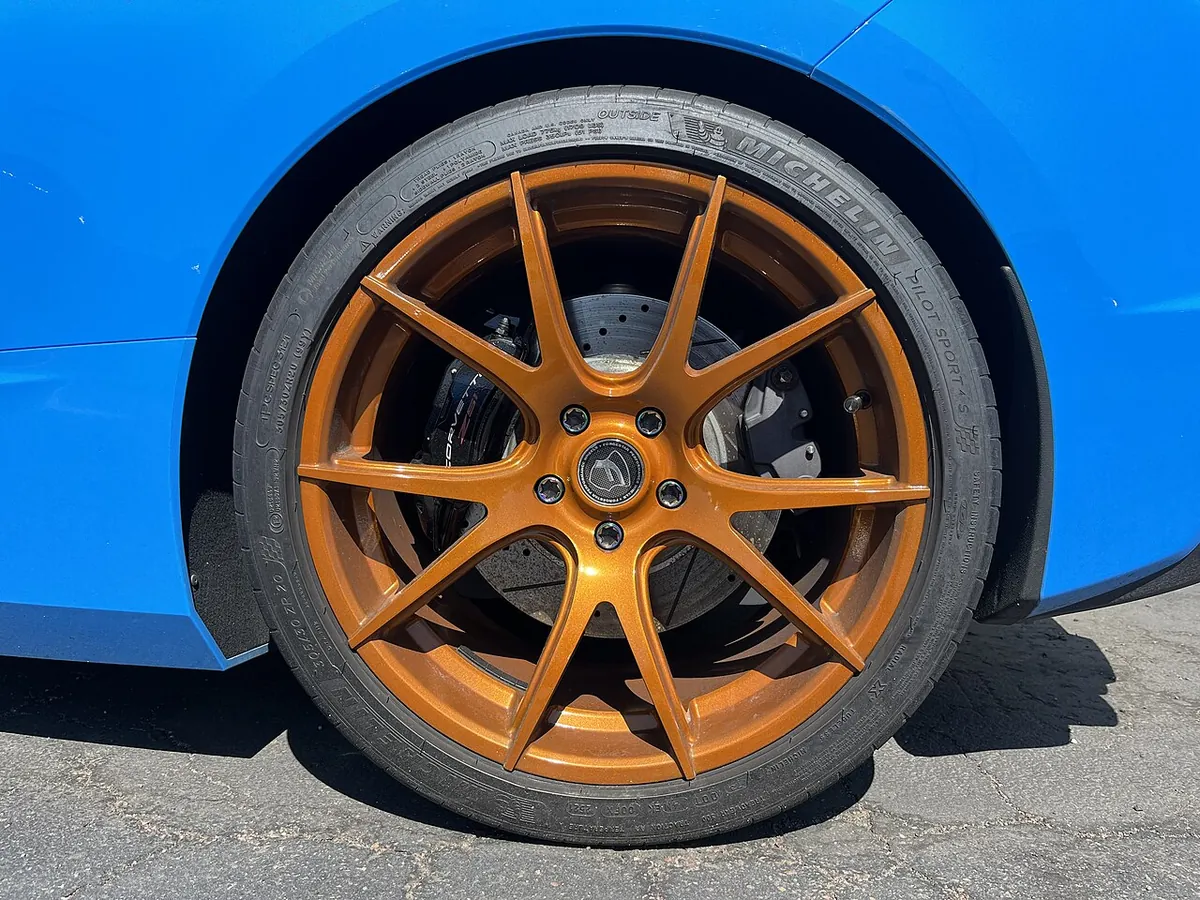 An aftermarket alloy wheel and low-profile tyre on the rear of a blue Chevrolet Corvette
