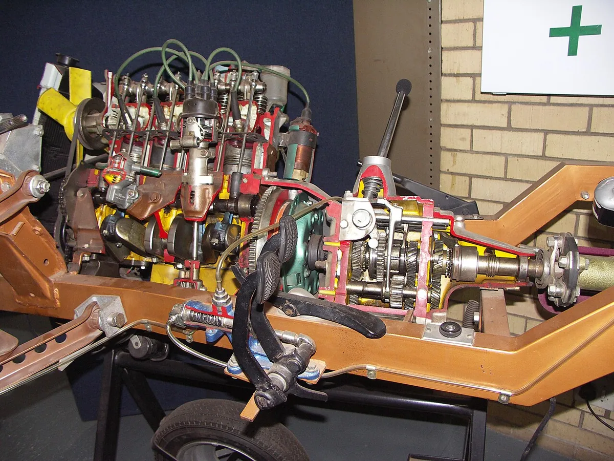 A sectioned engine and manual gearbox on a museum display stand, showing the clutch, gear clusters and shafts