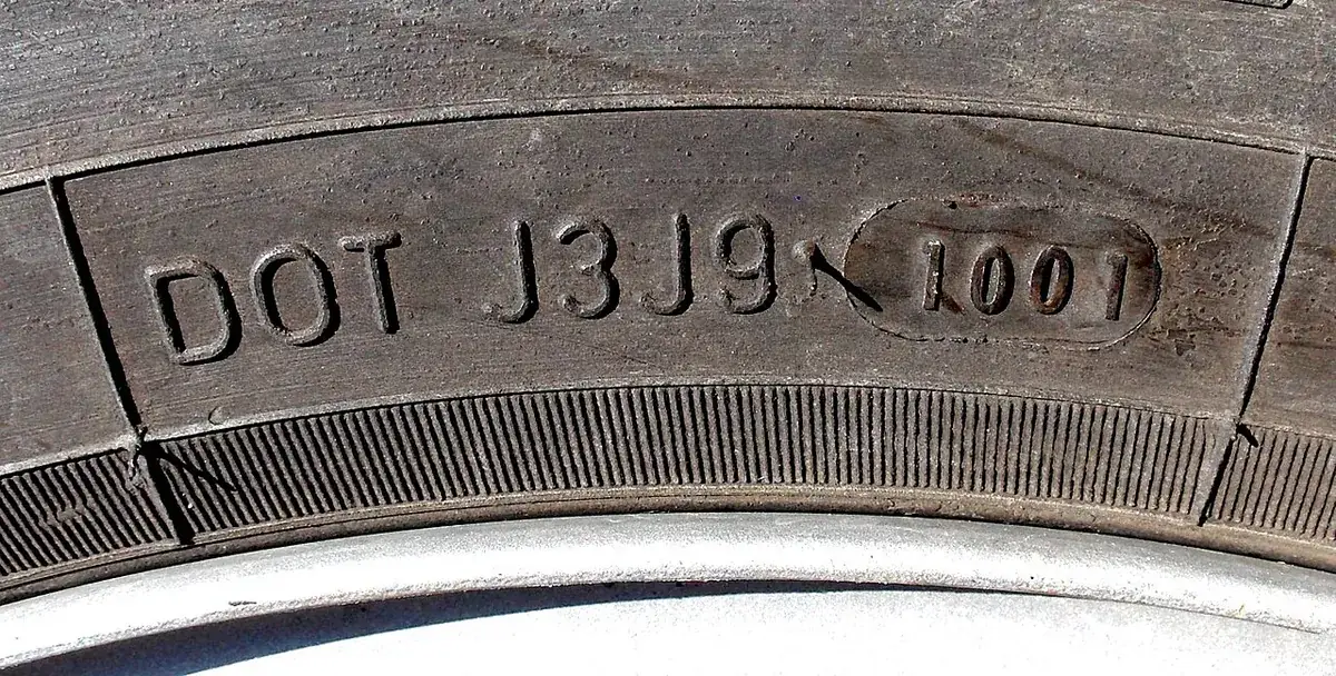 Close-up of a tyre sidewall showing DOT J3J9 1001, a date code for week 10 of 2001
